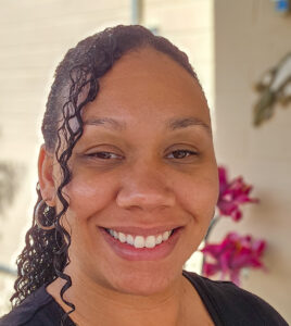 Calesse ‘Curly,’ creator of Curly Creates, smiling outdoors with natural curls and warm lighting.