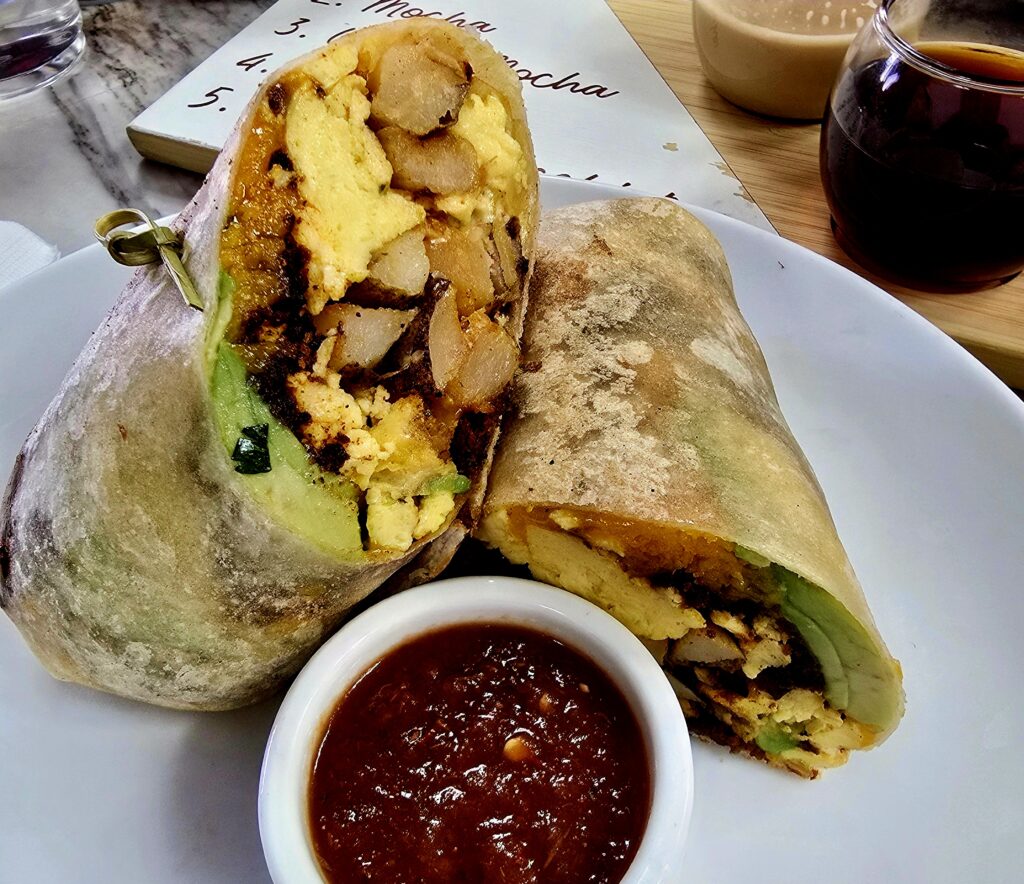 Breakfast burrito filled with scrambled eggs, potatoes, cheese, avocado, and bacon with salsa on the side at JoJo Coffeehouse.