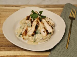Creamy lemon garlic Parmesan chicken sliced and served over mashed potatoes, topped with wilted spinach and finished with fresh herbs.