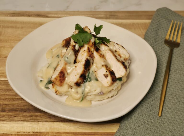 Creamy lemon garlic Parmesan chicken sliced and served over mashed potatoes, topped with wilted spinach and finished with fresh herbs.