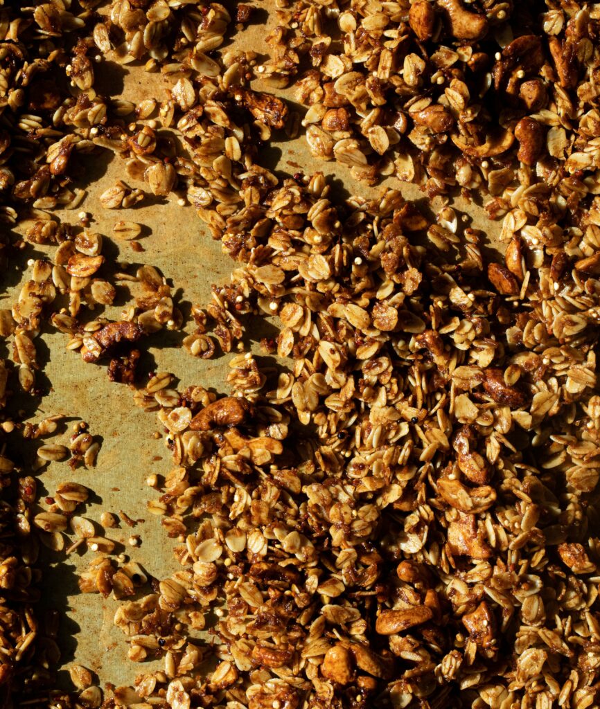 Granola clusters baked on a sheet pan, showing loose oats and nuts
